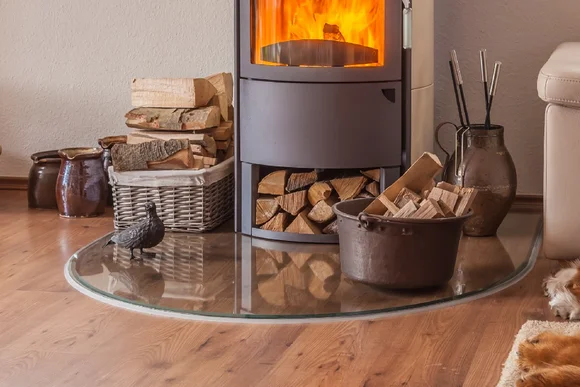 Ein moderner Kaminofen mit Brennholz und Kaminbesteck.